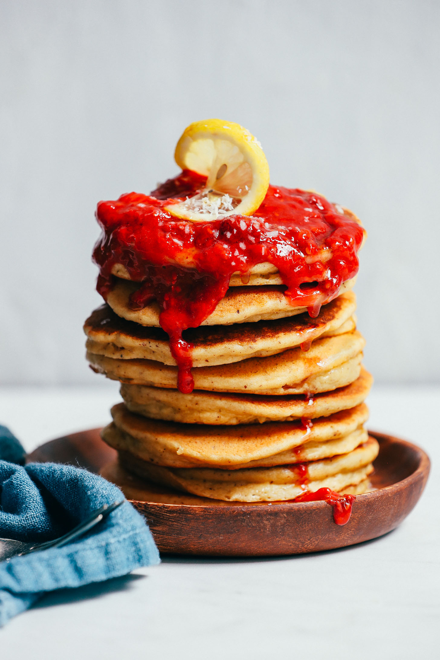 Stack of fluffy, low sugar, Grain-Free Pancakes with berry compote dripping down them