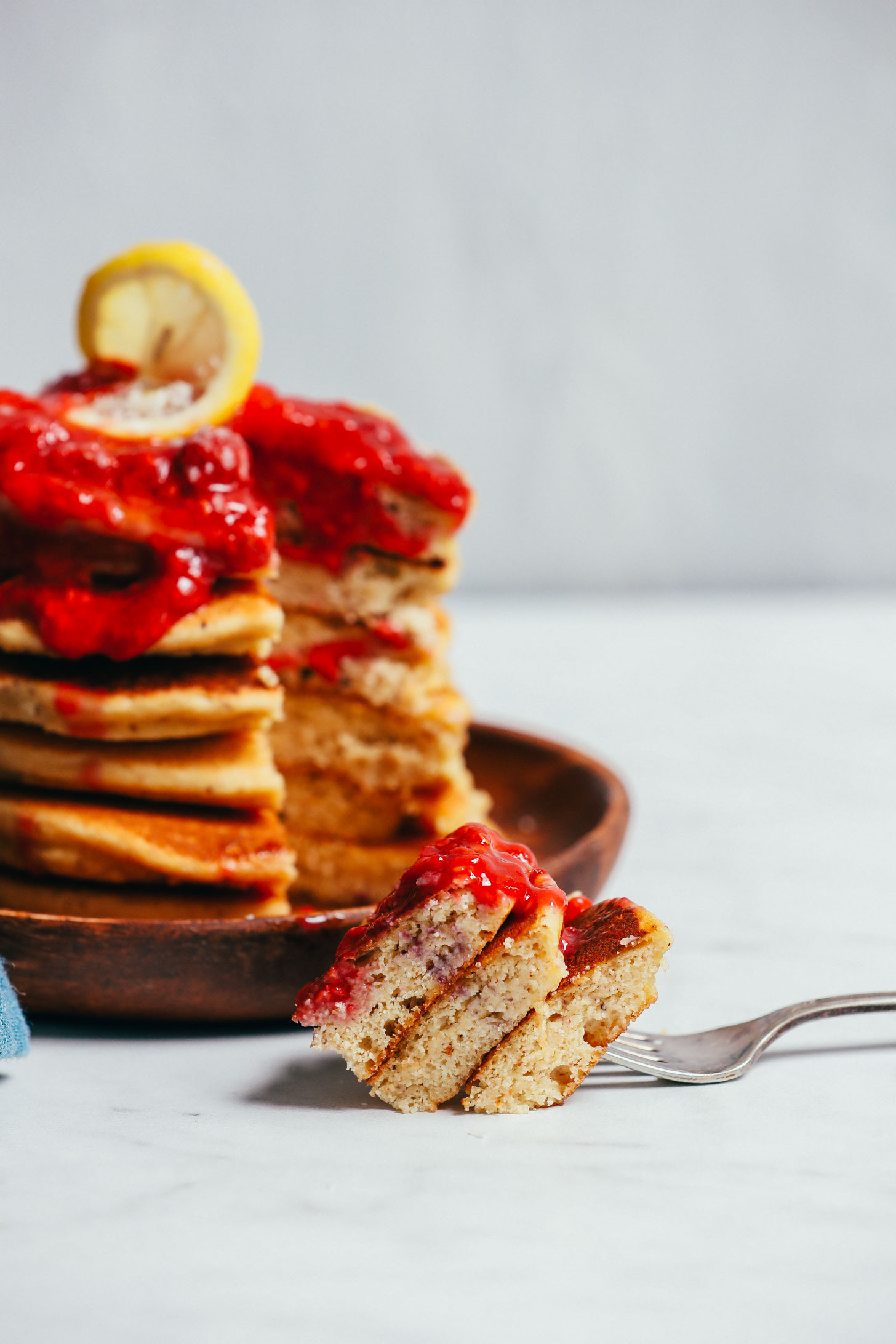 Bite of Grain-Free Pancakes with berry compote resting on a fork beside a plate
