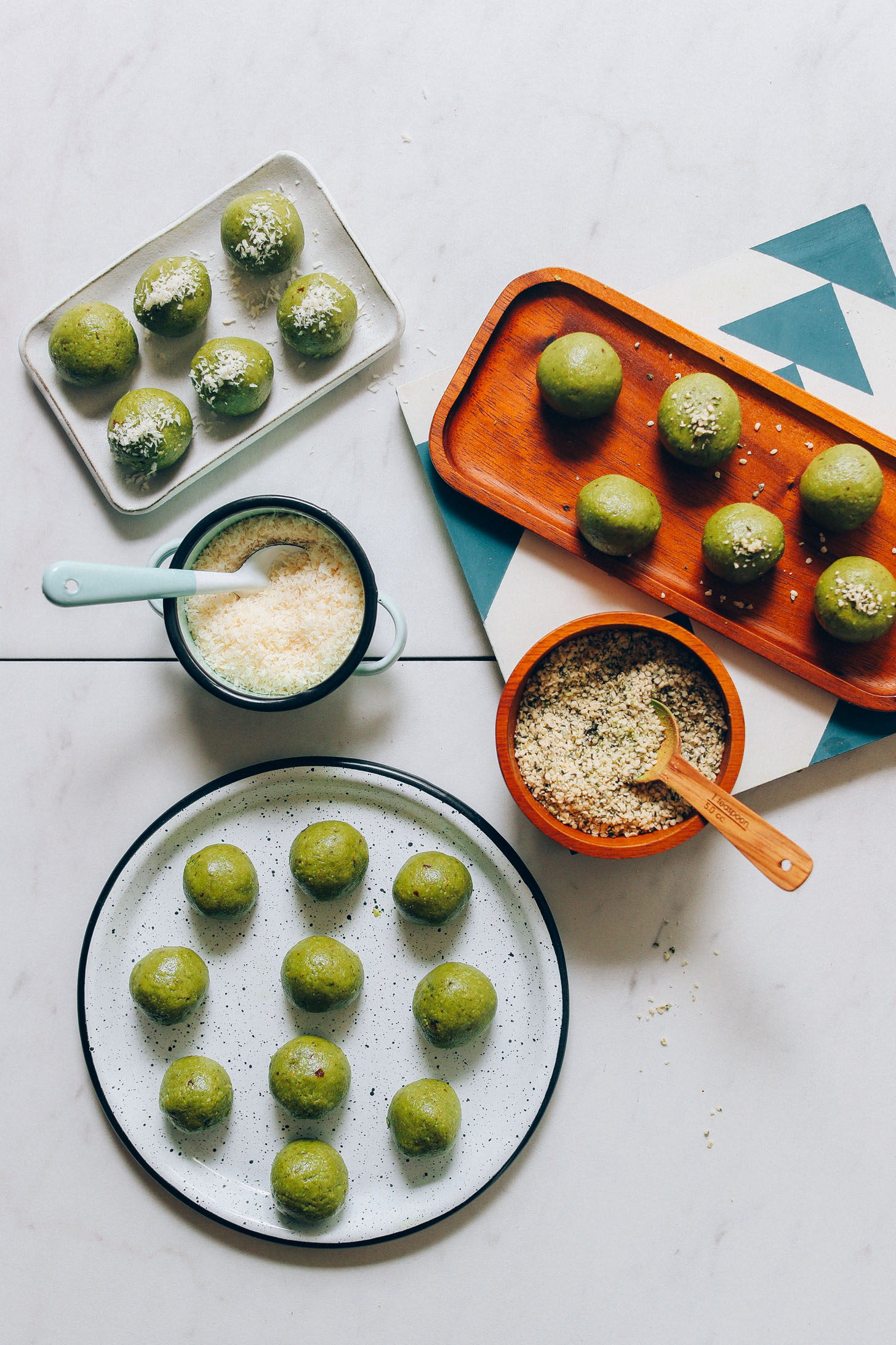 Plates of Matcha Bliss Balls with bowls of shredded coconut and hemp seeds for topping