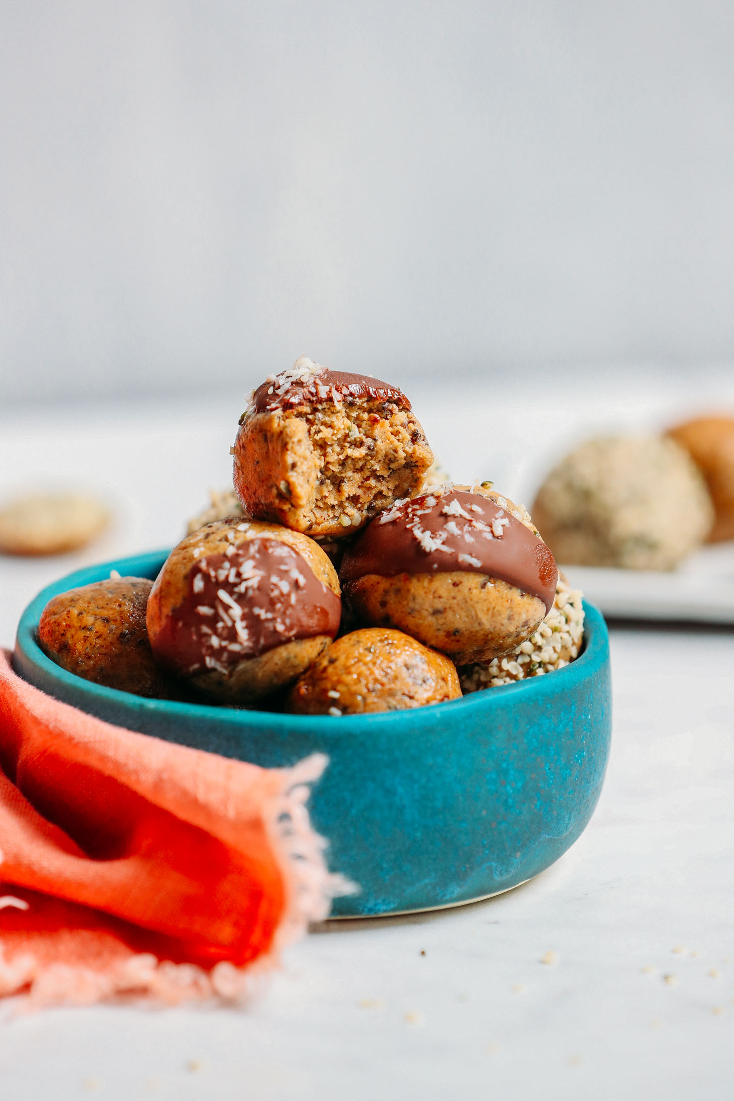 Bowl piled high with gluten-free Protein Balls topped with dark chocolate and shredded coconut