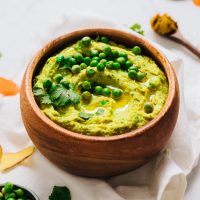 Bowl of Green Pea Curry Hummus topped with peas
