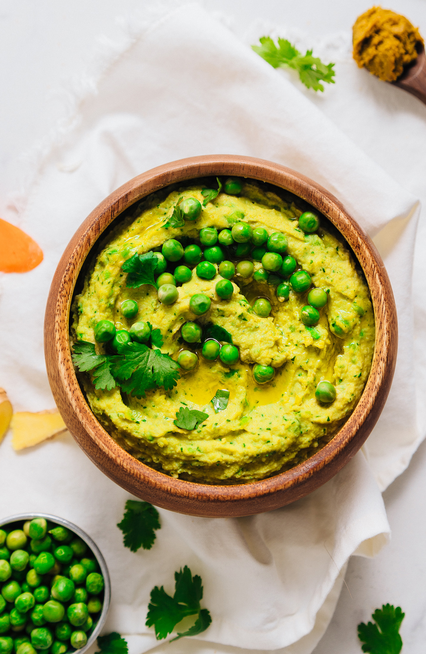 Top down shot of a wood bowl of Green Pea Curry Hummus for a delicious veggie-packed dip