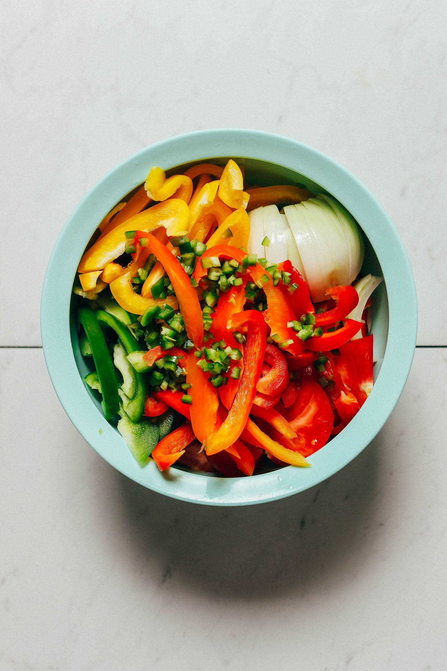 Large bowl filled with sliced vegetables for making our delicious Baked White Fish recipe