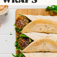 Kale falafel hummus wraps on a cutting board with text above them saying ready in 30 minutes