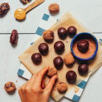 overhead image of date sweetened truffles on a blue and white tile being dipped into cacao powder