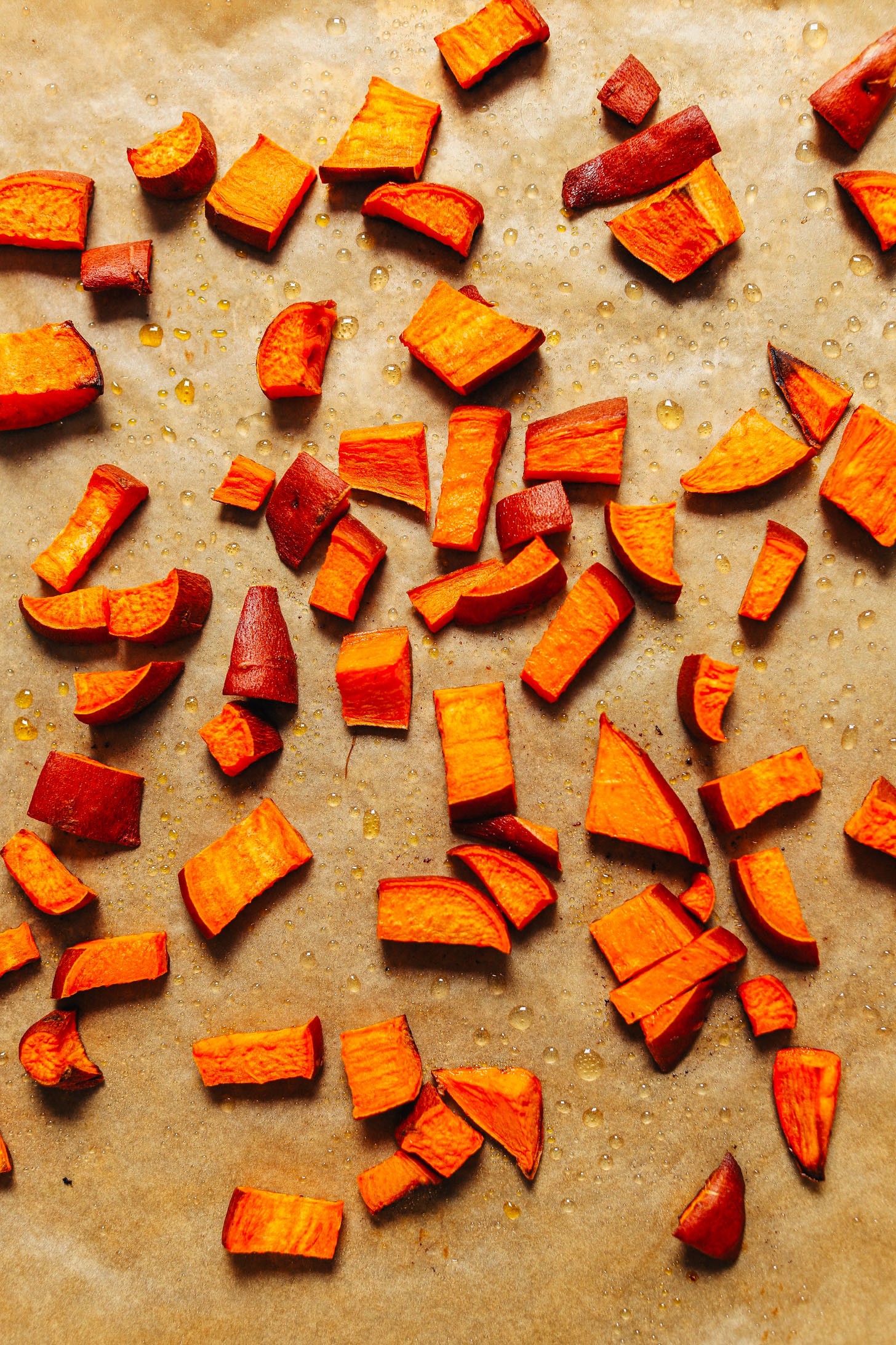 Freshly roasted cubed sweet potatoes on a parchment-lined baking sheet