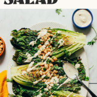 Platter of grilled romaine topped with lemon-herb white beans and a vegan caesar dressing
