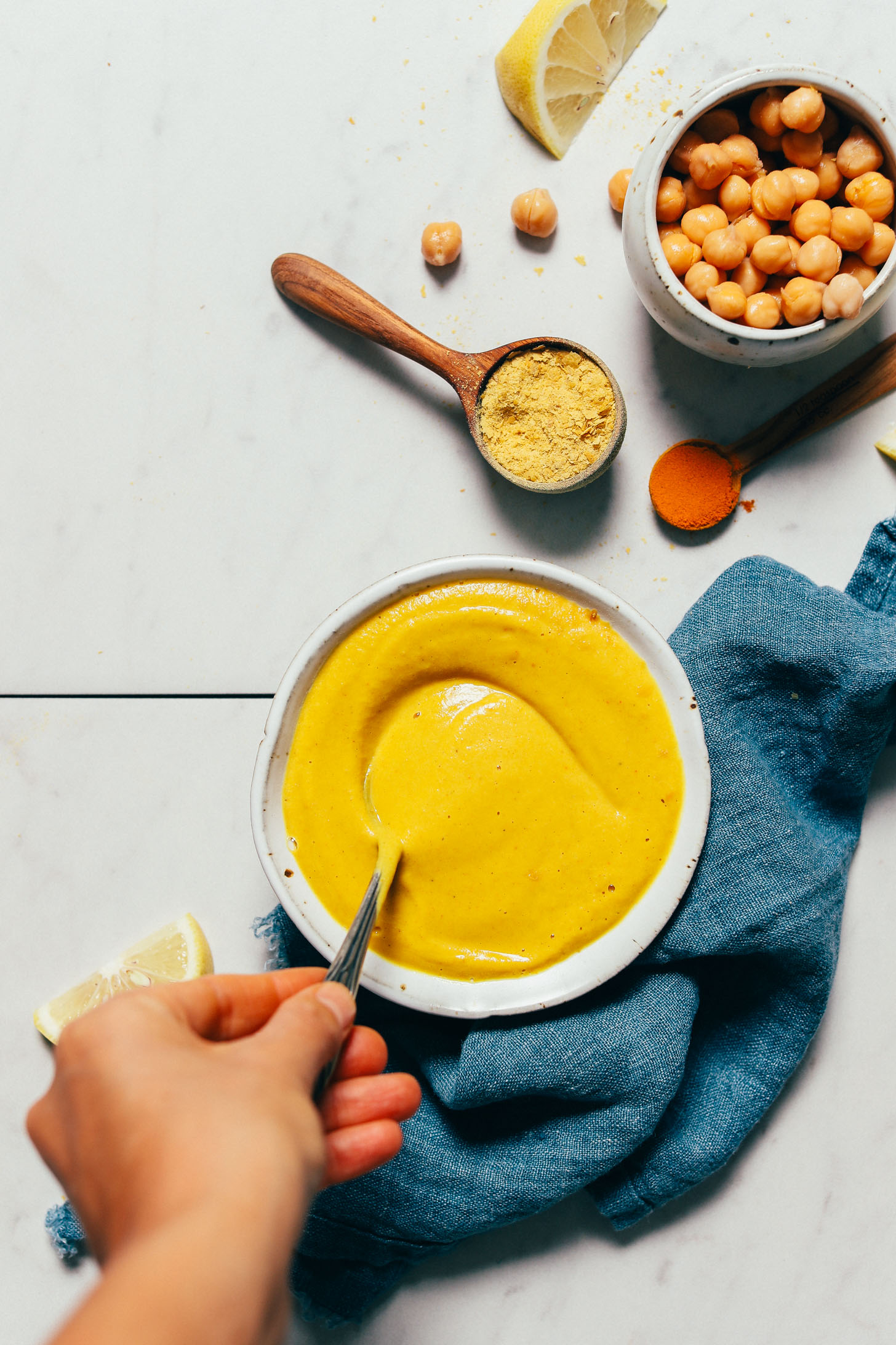 Stirring a bowl of our Liquid Gold Sauce recipe made from chickpeas and nutritional yeast