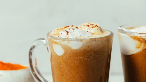 Mugs of our easy DIY Pumpkin Spice Latte topped with coconut whipped cream and pumpkin pie spice