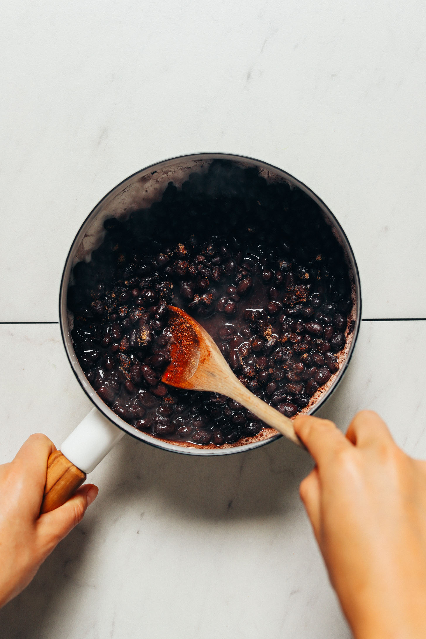 Stirring seasonings into a pot of black beans