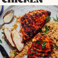 Bowl with two marinated grilled chicken breasts over a plate of quinoa