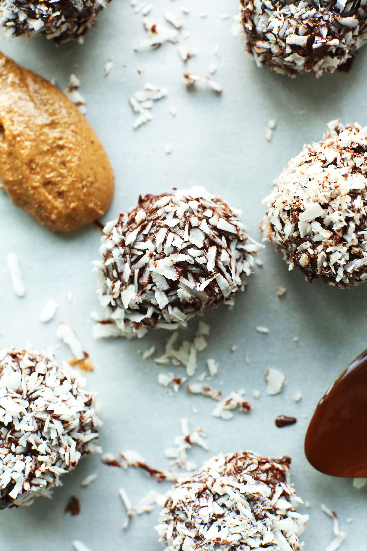 Spoonfuls of almond butter and melted dark chocolate beside Dark Chocolate Almond Butter Snowballs