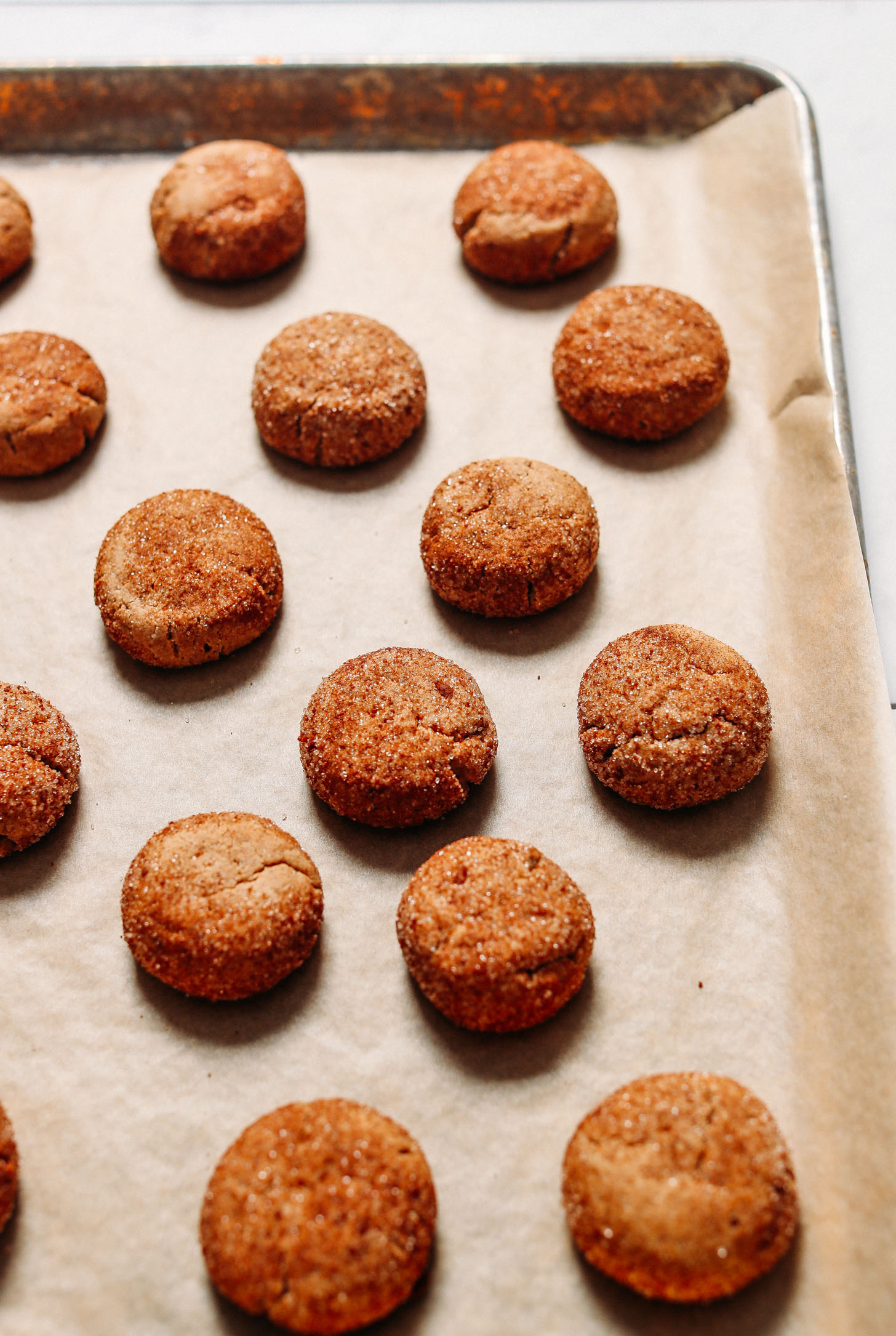 Freshly baked batch of healthy Snickerdoodle Cookies on a parchment-lined baking sheet