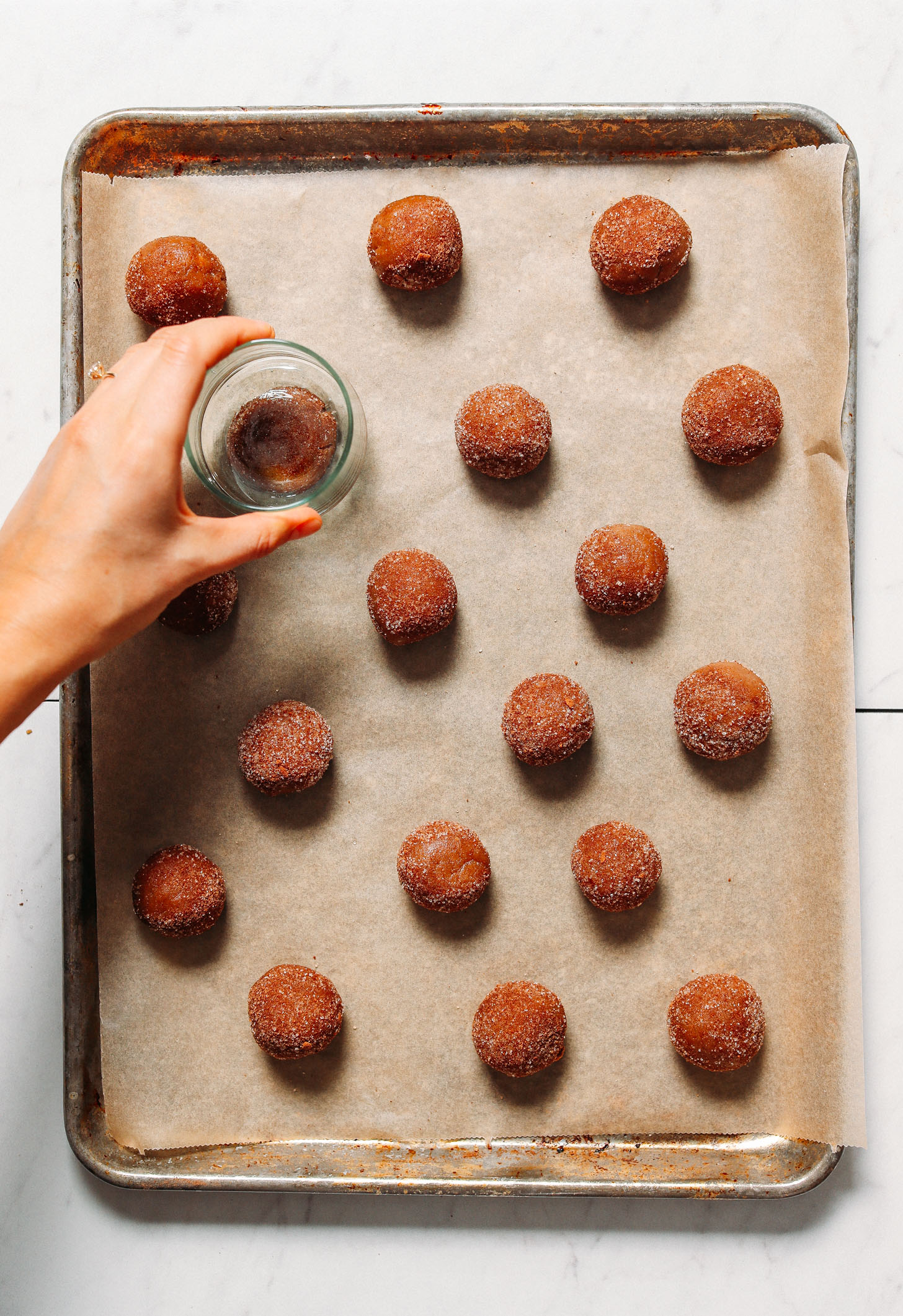Using a glass to flatten a batch of our Gluten-Free Vegan Snickerdoodle Cookies
