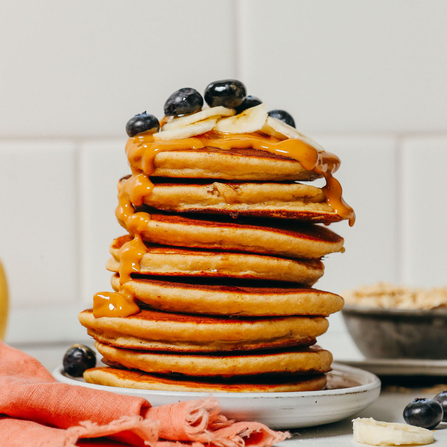 Stack of Blender Banana Pancakes topped with nut butter and fresh fruit