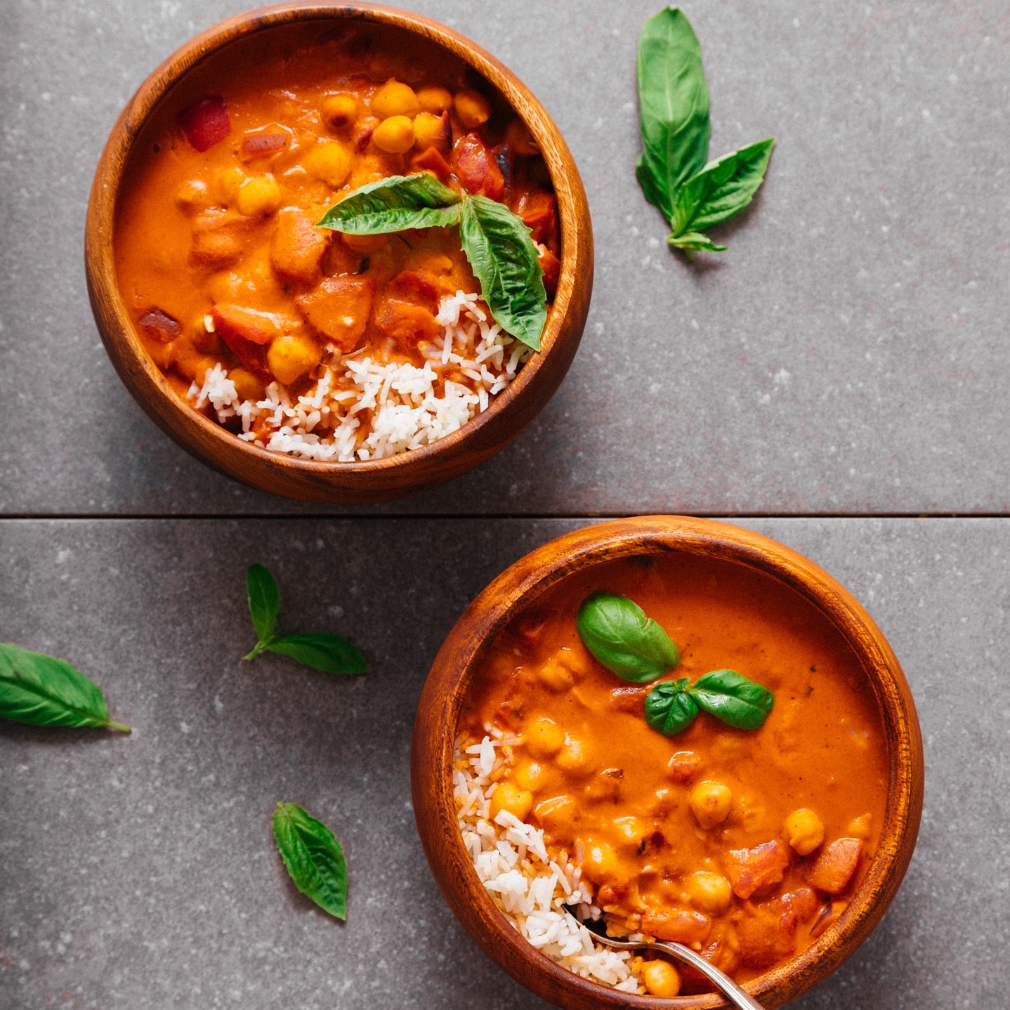 Bowls of Chickpea Tomato Peanut Stew served with rice and fresh basil