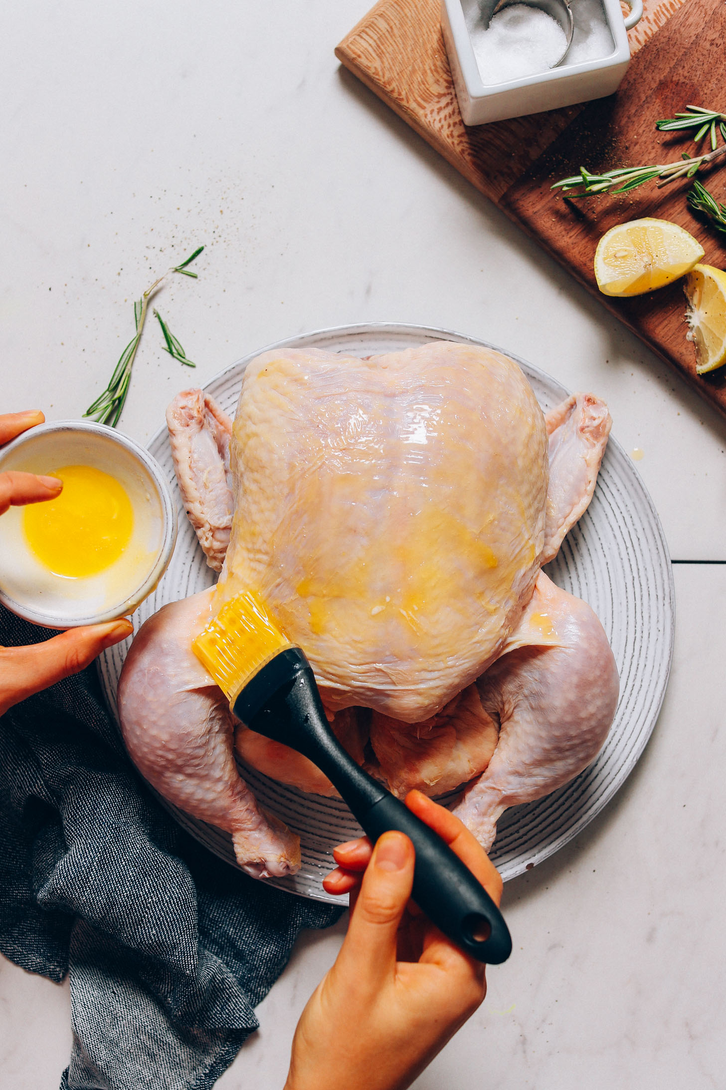 Brushing butter onto the skin of a chicken to make our crispy skin Roasted Chicken recipe