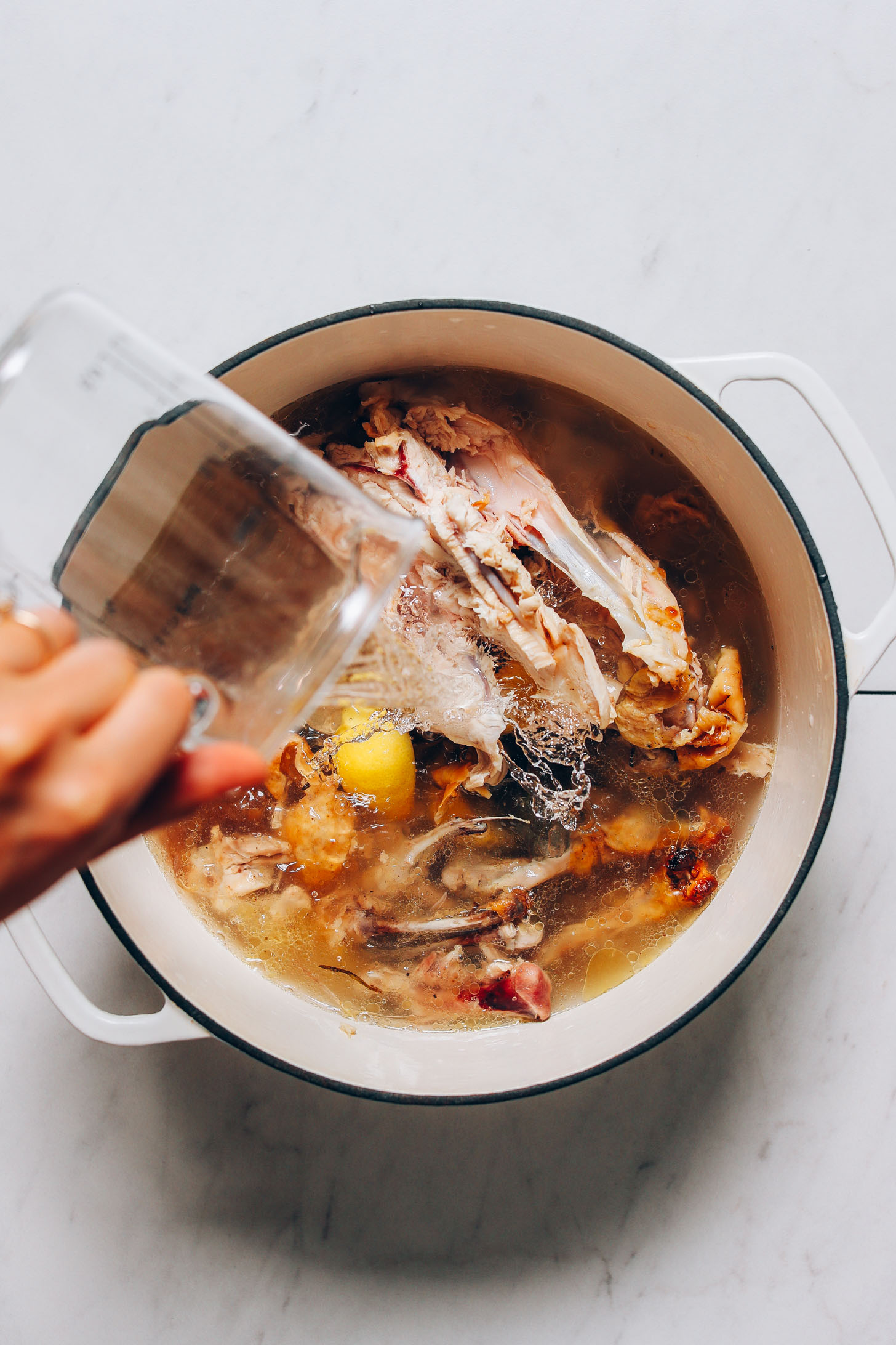Pouring water over a chicken carcass for our tutorial on How to Make Bone Broth