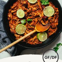 Skillet of our Shredded Mexican Chicken recipe topped with cilantro and lime slices