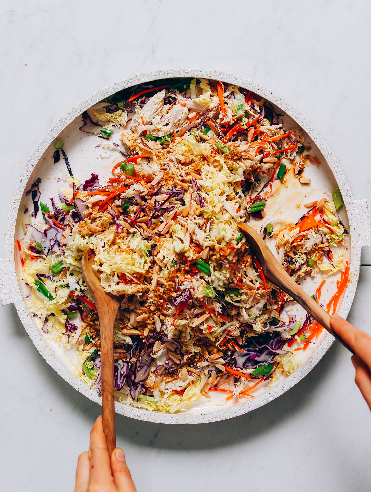 Using salad tongs to pick up a serving of Crunchy Cabbage Slaw made without soy or gluten