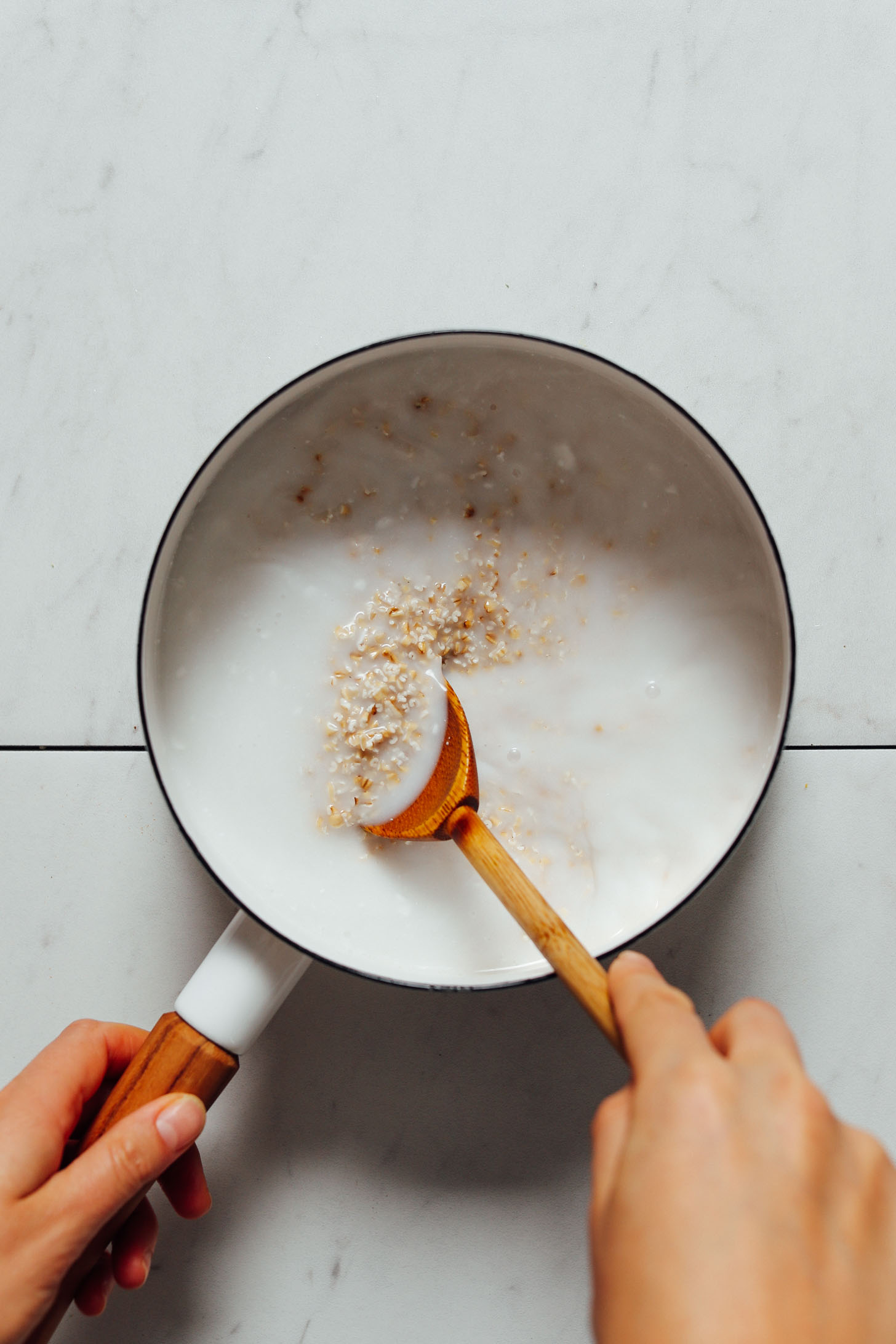 Using a wooden spoon to stir a pan of steel cut oats
