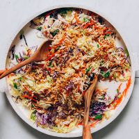 Using salad tongs to pick up a serving of gluten-free Crunchy Cabbage Slaw with Sesame Ginger Dressing