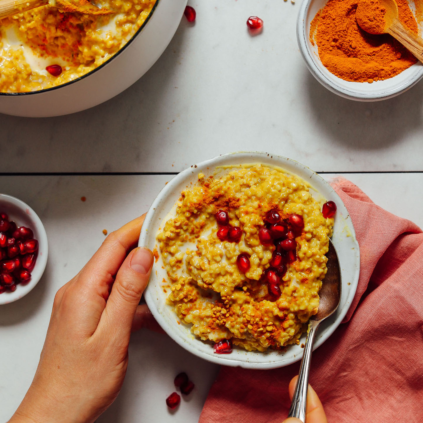 Spoon in a bowl of Cozy Turmeric Porridge with pomegranate arrils