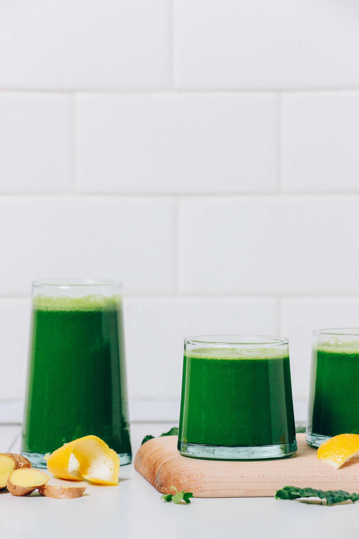 Side view of glasses of Green Juice made with celery, lemon, ginger, and more