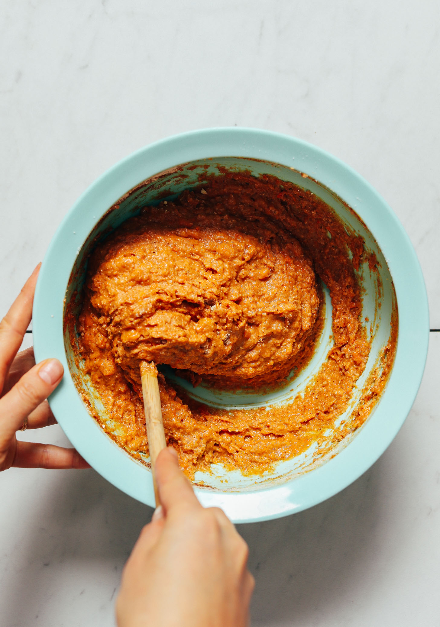 Using a wooden spoon to stir the batter for our Almond Butter Sweet Potato Muffins recipe