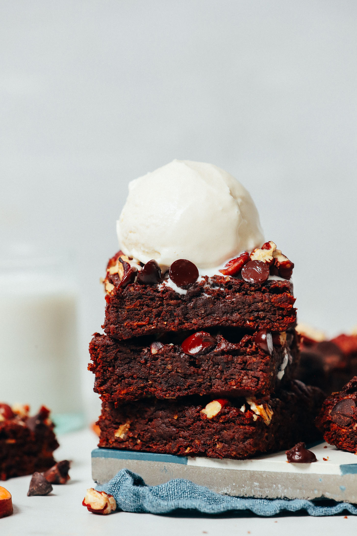 Stack of Sweet Potato Brownies topped with chocolate chips, pecans, and vanilla ice cream