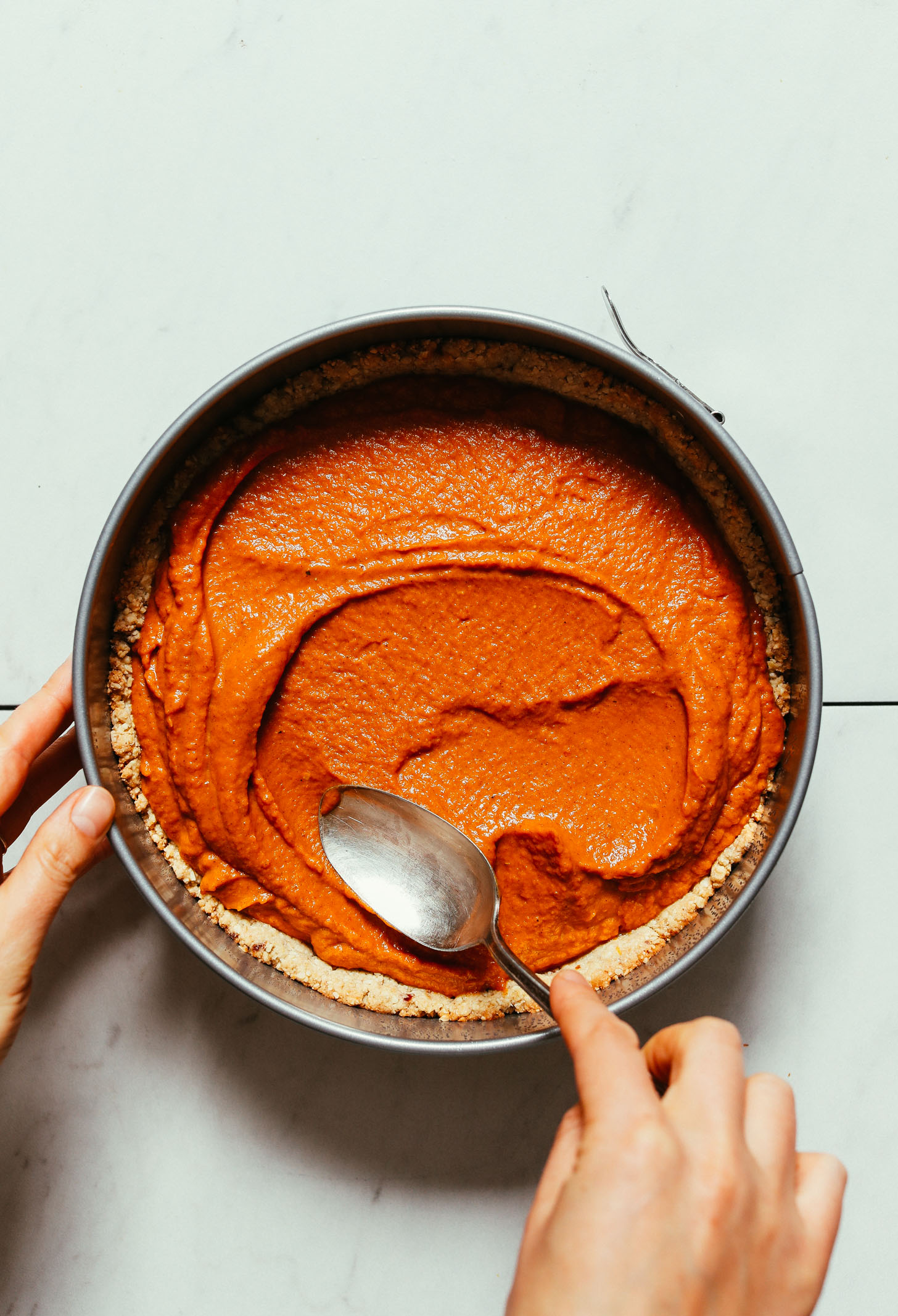 Using a spoon to spread filling into our Vegan Gluten-Free Pumpkin Pie Crust
