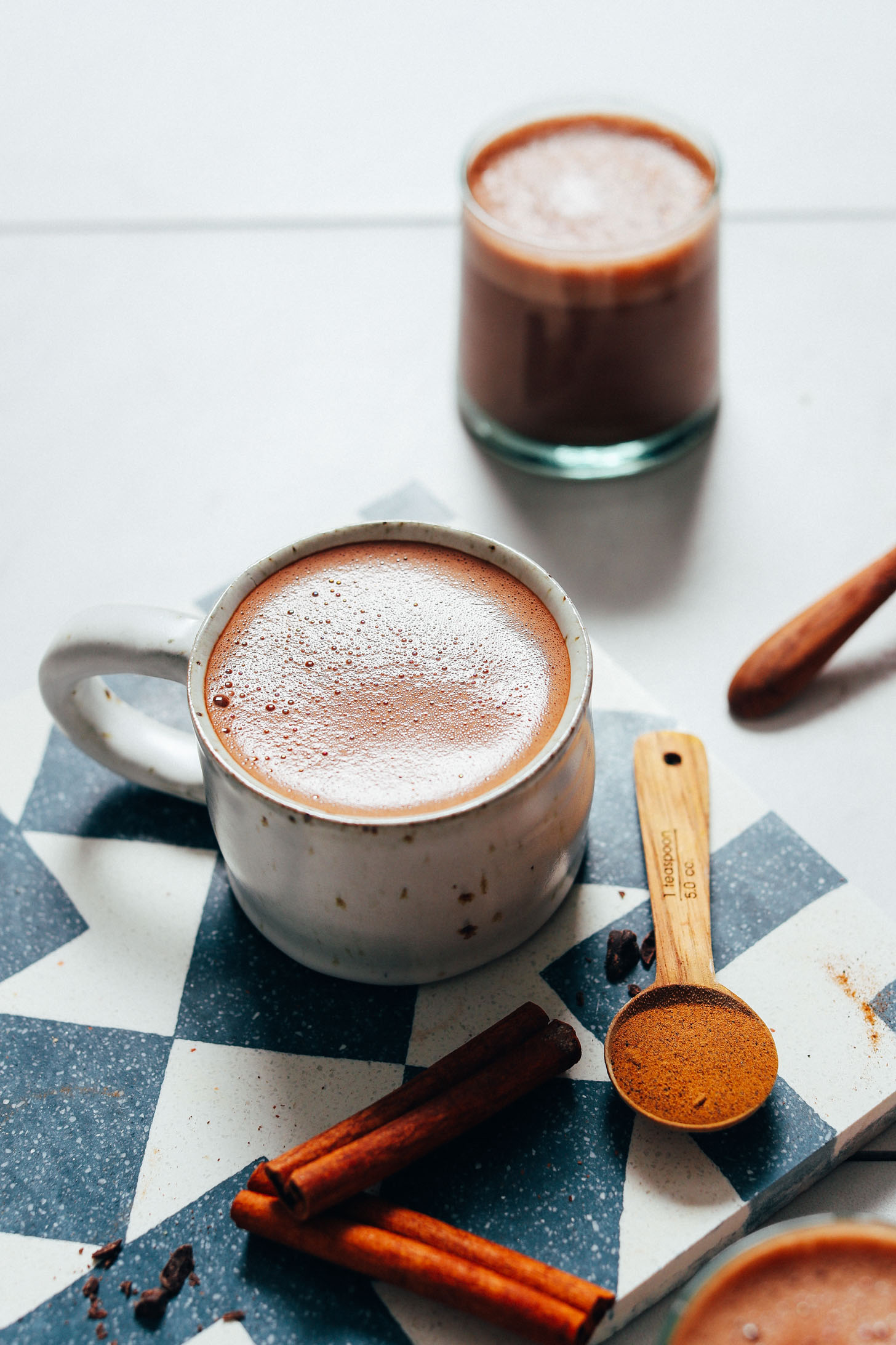 Mug and glass of vegan hot chocolate with adaptogens and cinnamon