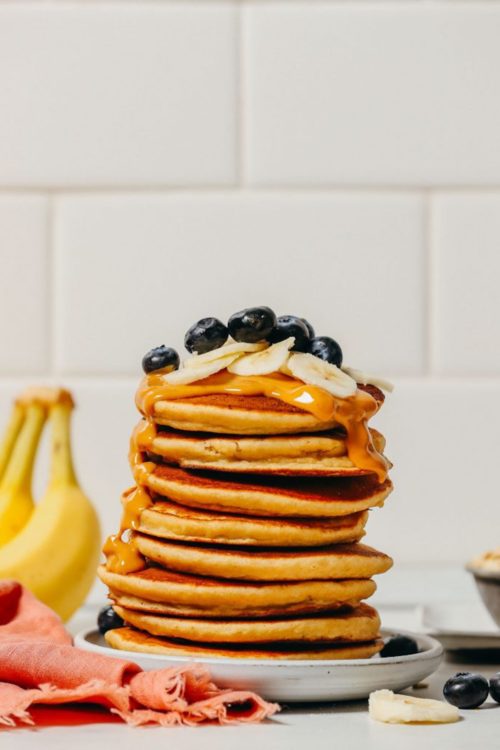 Stack of Blender Banana Pancakes topped with peanut butter and fresh fruit