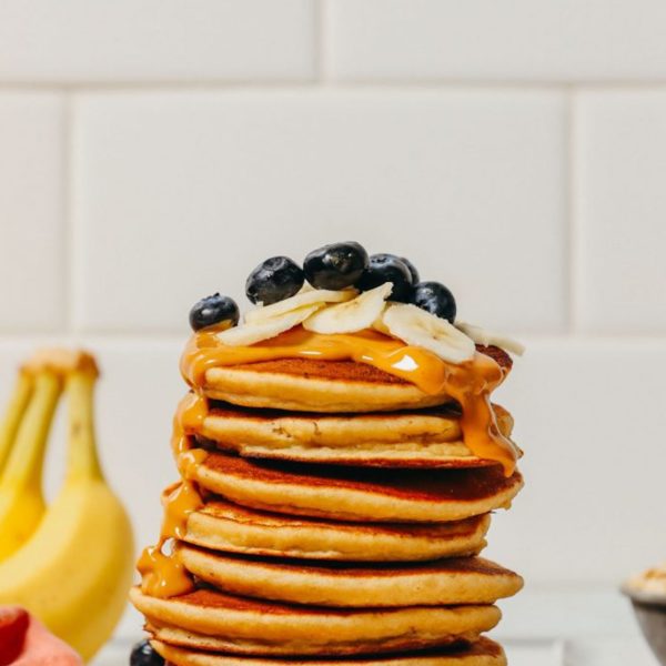 Stack of Blender Banana Pancakes topped with peanut butter and fresh fruit