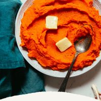 Bowl of Fluffy Mashed Sweet Potatoes and Carrots topped with squares of vegan butter