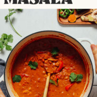 Hands holding the handles of a Dutch oven filled with our easy 1-pot tikka masala recipe with a vegan option