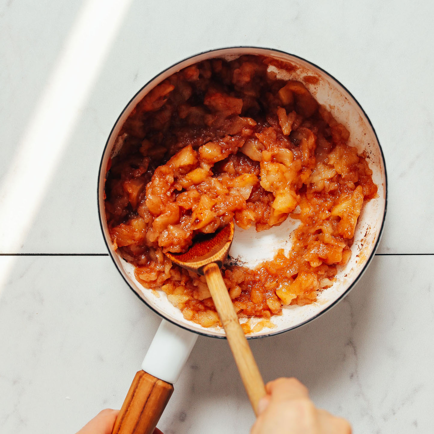 Using a wooden spoon to stir a pan of our easy Applesauce recipe