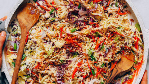 Holding a large serving dish filled with a batch of our Chinese Chicken Salad recipe