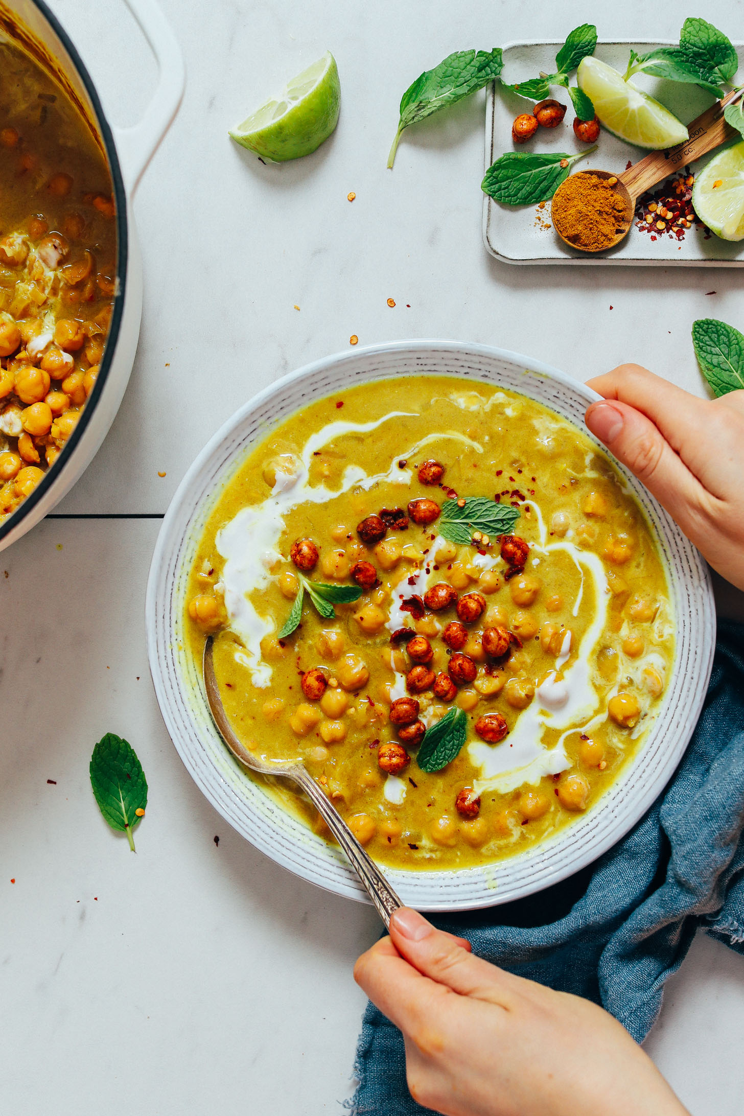 Holding the side of a bowl and a spoon in a bowl of Curried Chickpea Soup