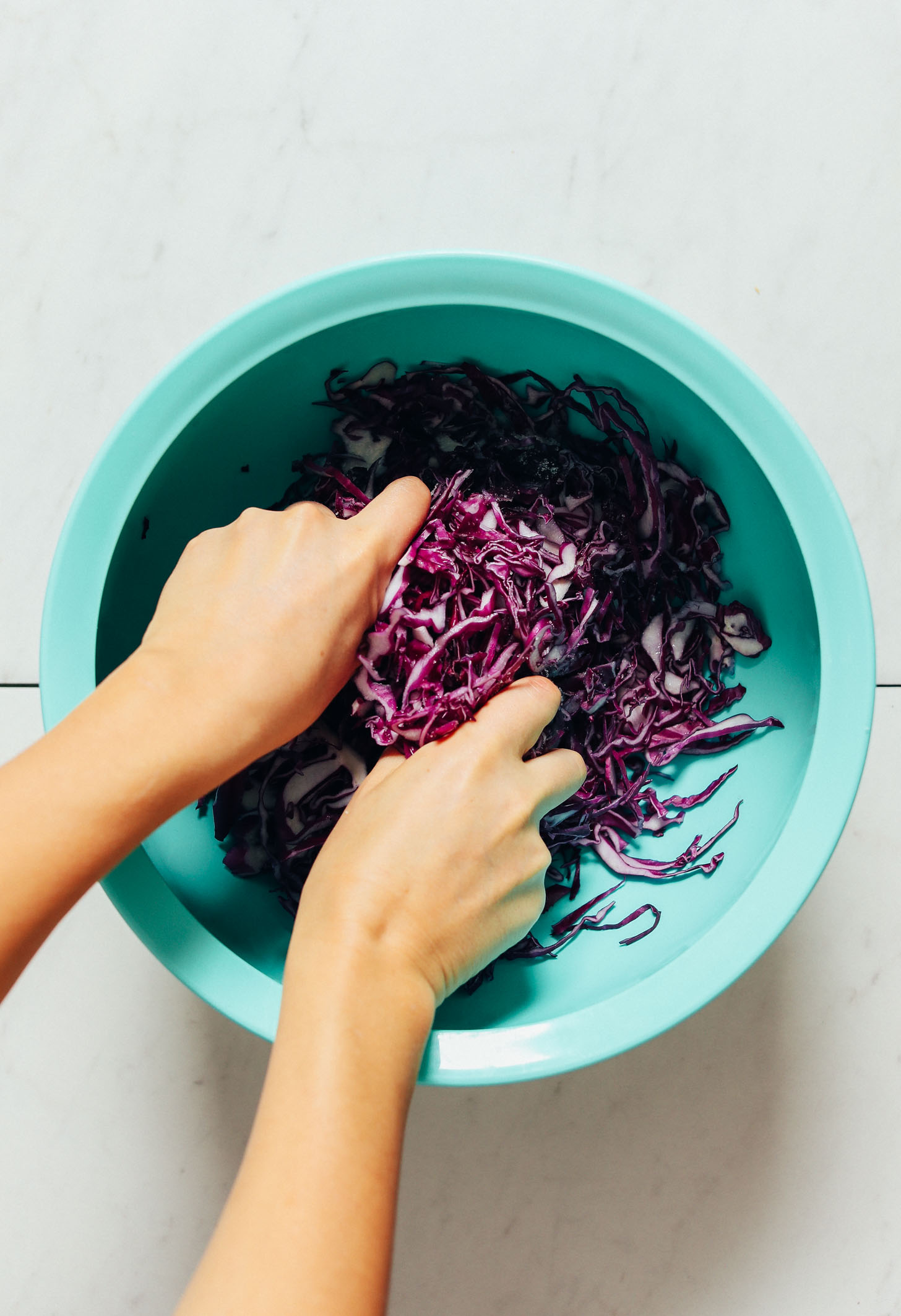 Hands massaging red cabbage to make homemade sauerkraut