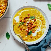Bowl of Curried Chickpea Soup topped with crispy chickpeas, coconut milk, and cilantro