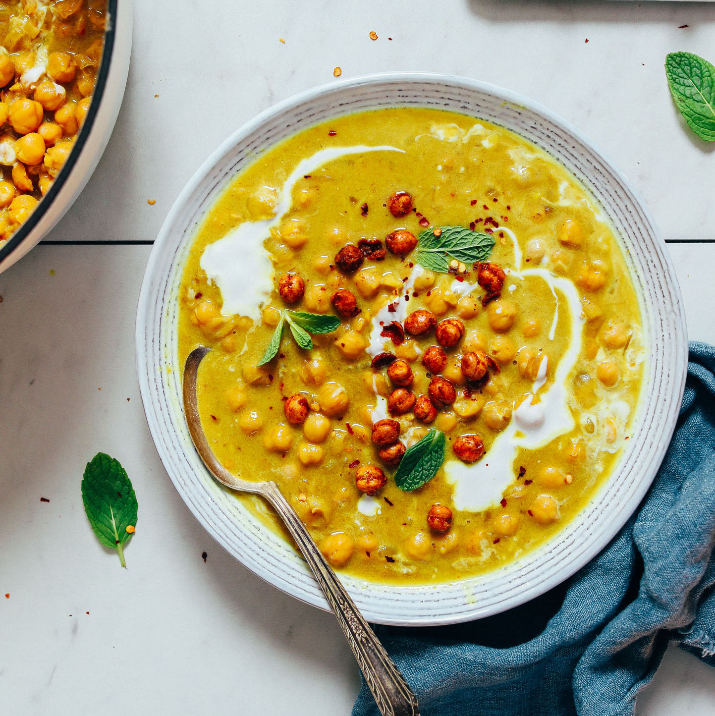 Bowl of Curried Chickpea Soup topped with crispy chickpeas, coconut milk, and cilantro