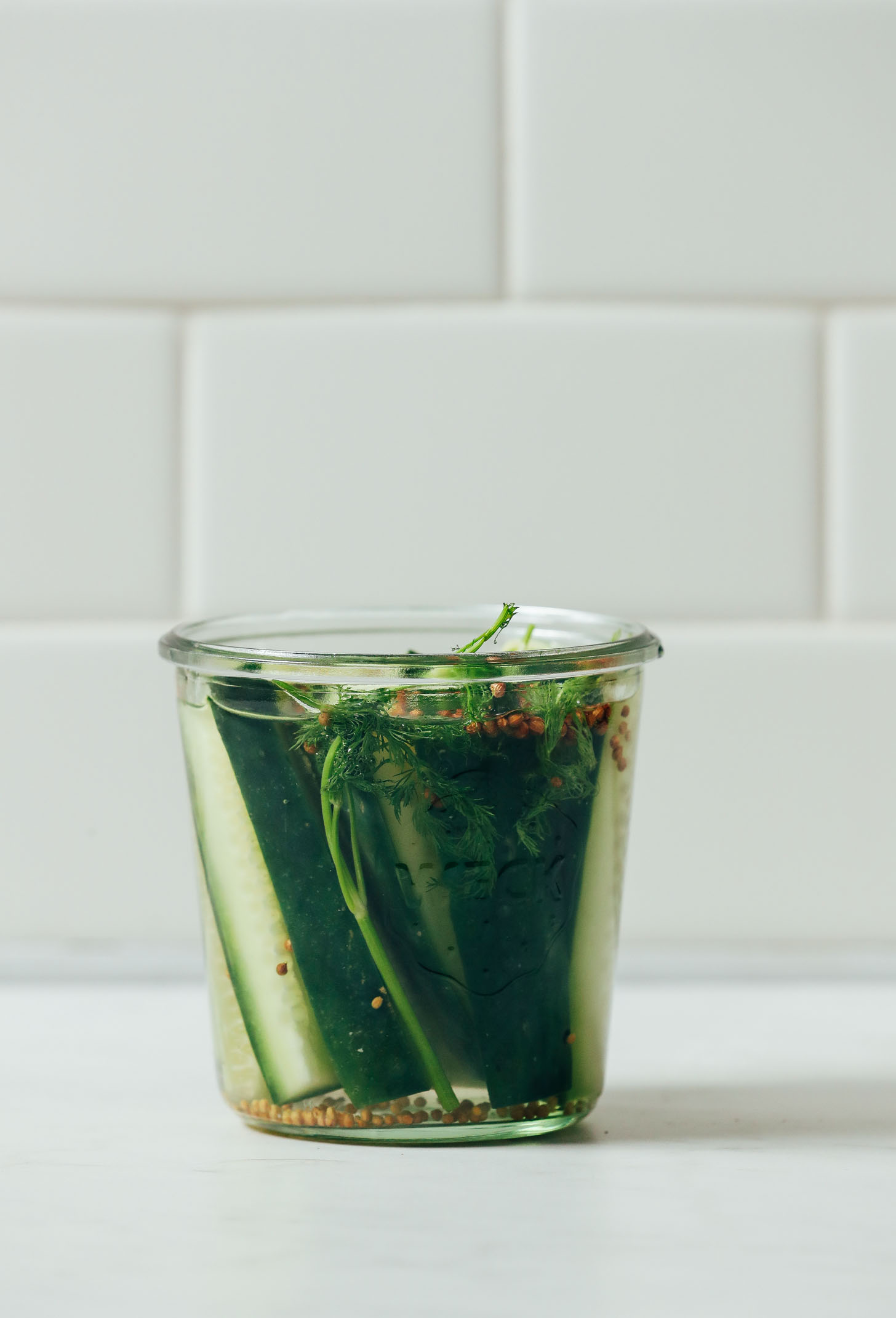 Jar of Quick Pickled Cucumbers made with mustard seeds, dill, and coriander seeds