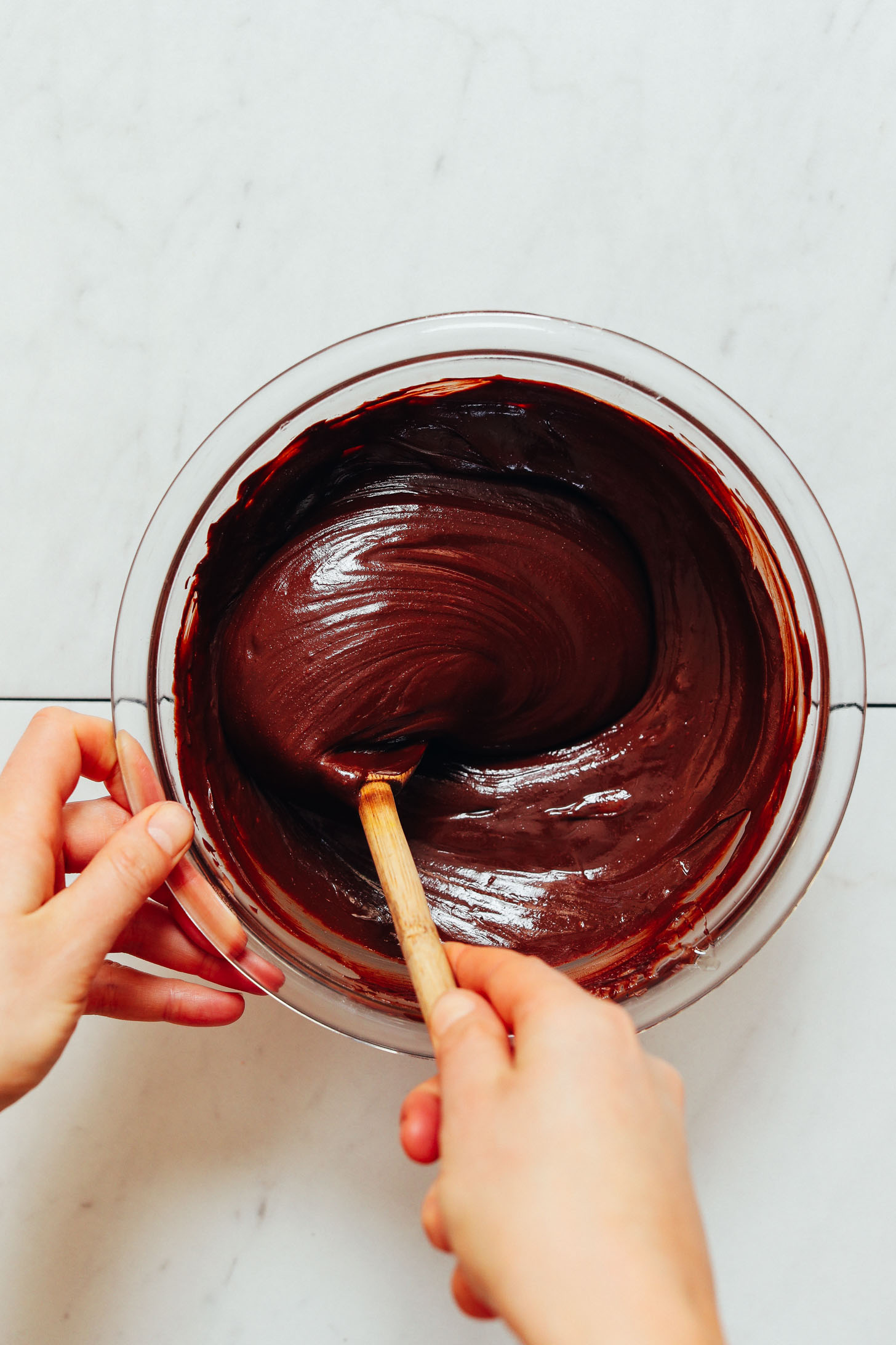 Using a wooden spoon to stir a bowl of batter for making 3-Ingredient Chocolate Fudge