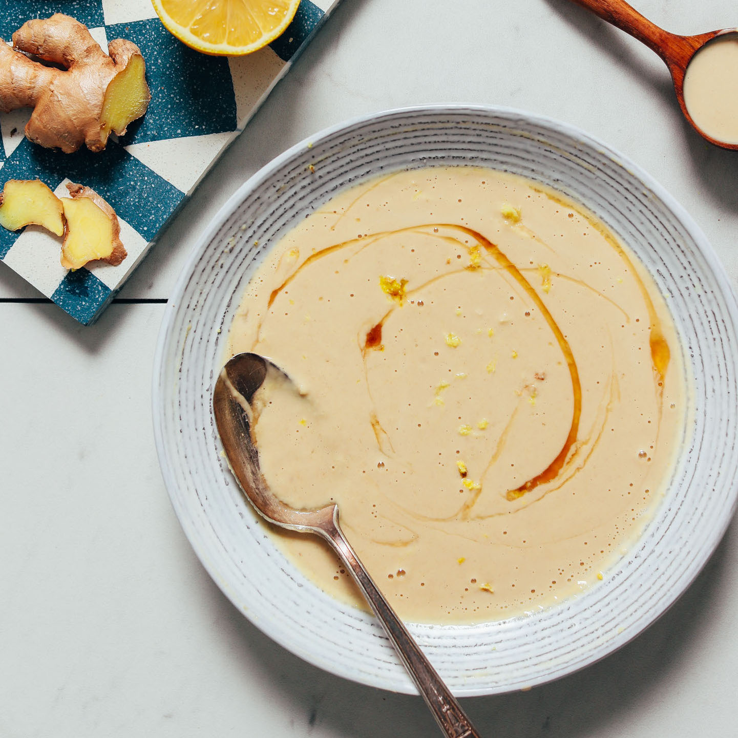 Spoon resting in a bowl of our Lemony Ginger Tahini Sauce