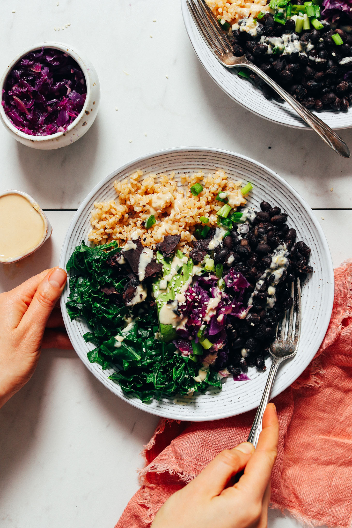 Fork in a Black Bean Buddha Bowl made with beans, rice, kale, avocado, kraut, and sauce