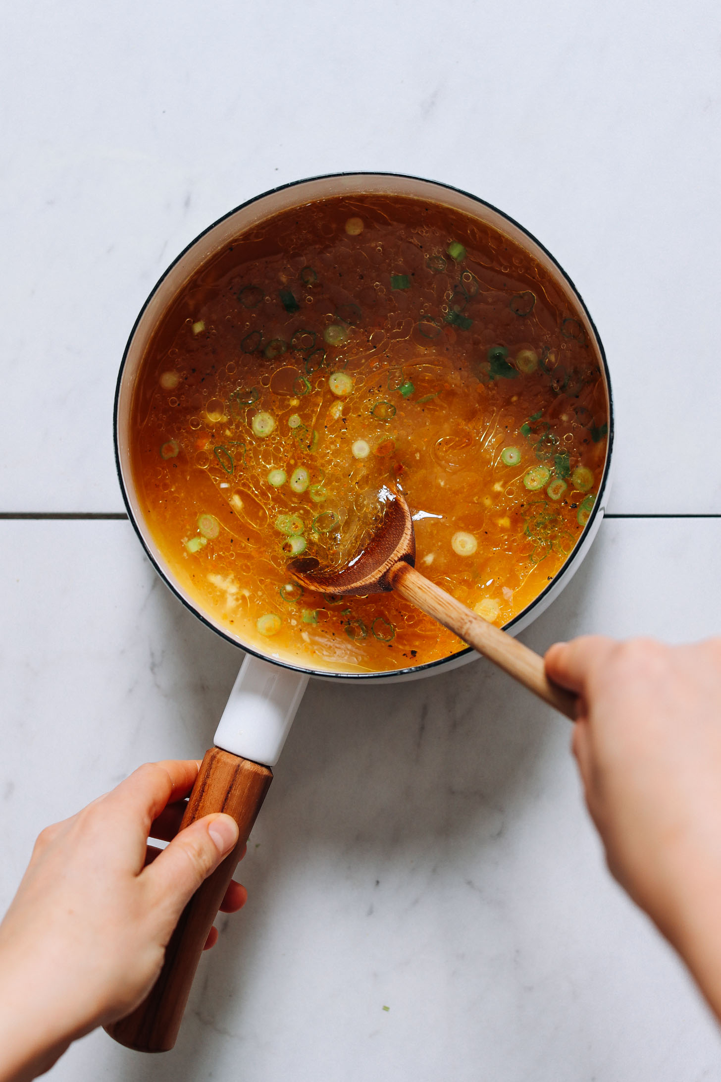 Using a wooden spoon to stir a pot of our Nourishing Bone Broth Tonic recipe