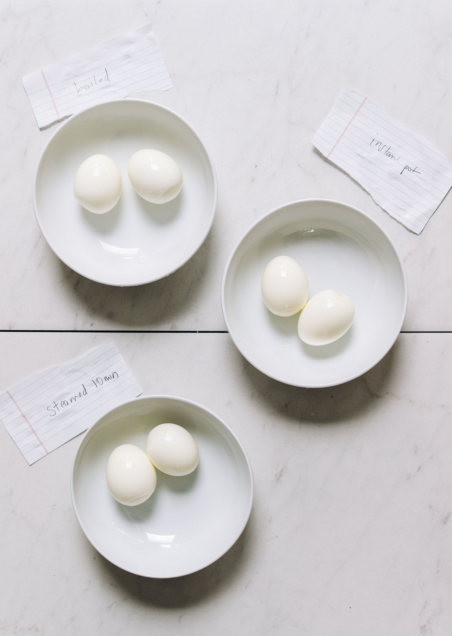 Bowls of perfectly cooked hard boiled eggs made using three methods: boiled, steamed, and in an Instant Pot