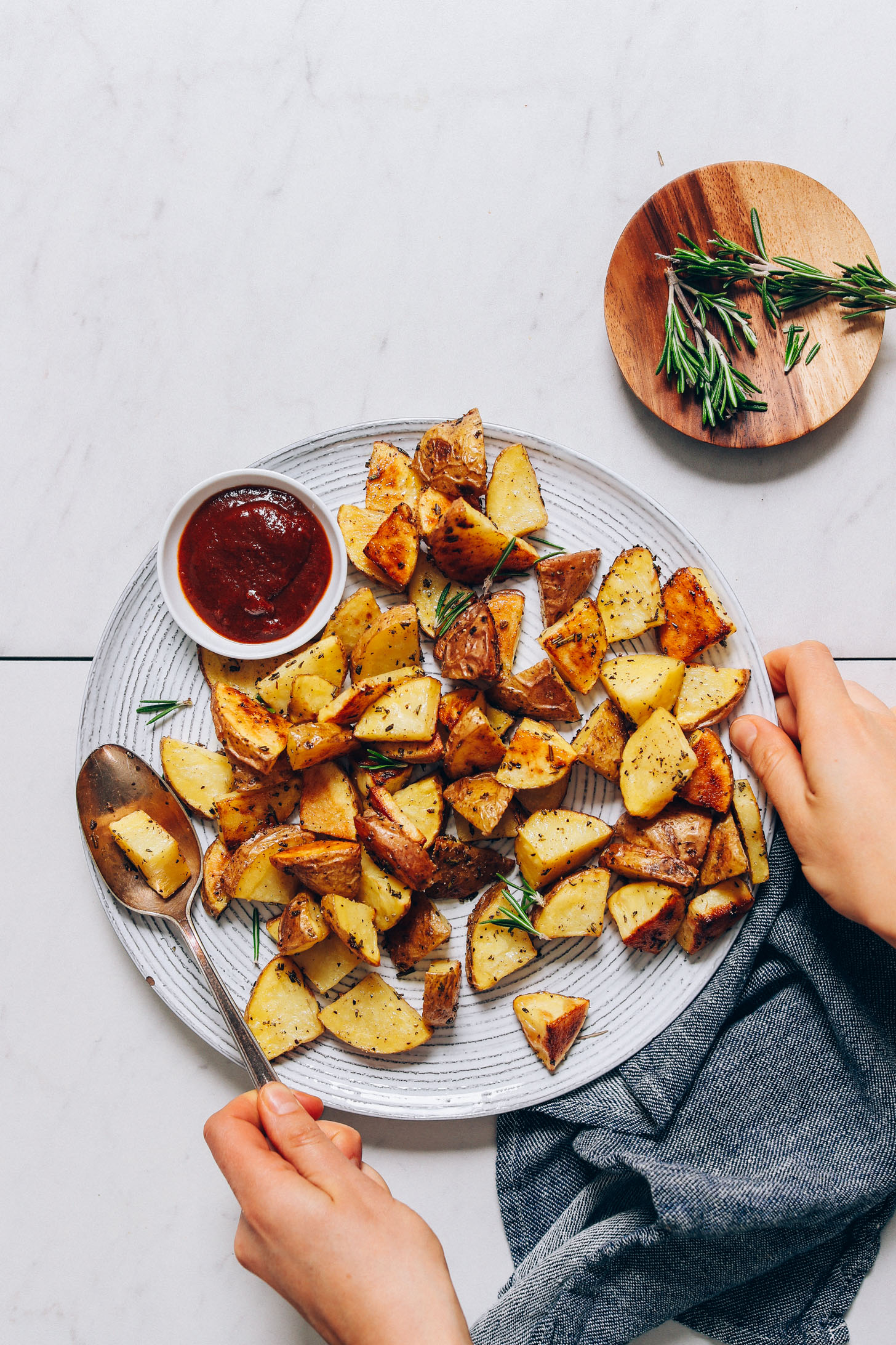 Holding the sides of a plate of Rosemary Roasted Potatoes
