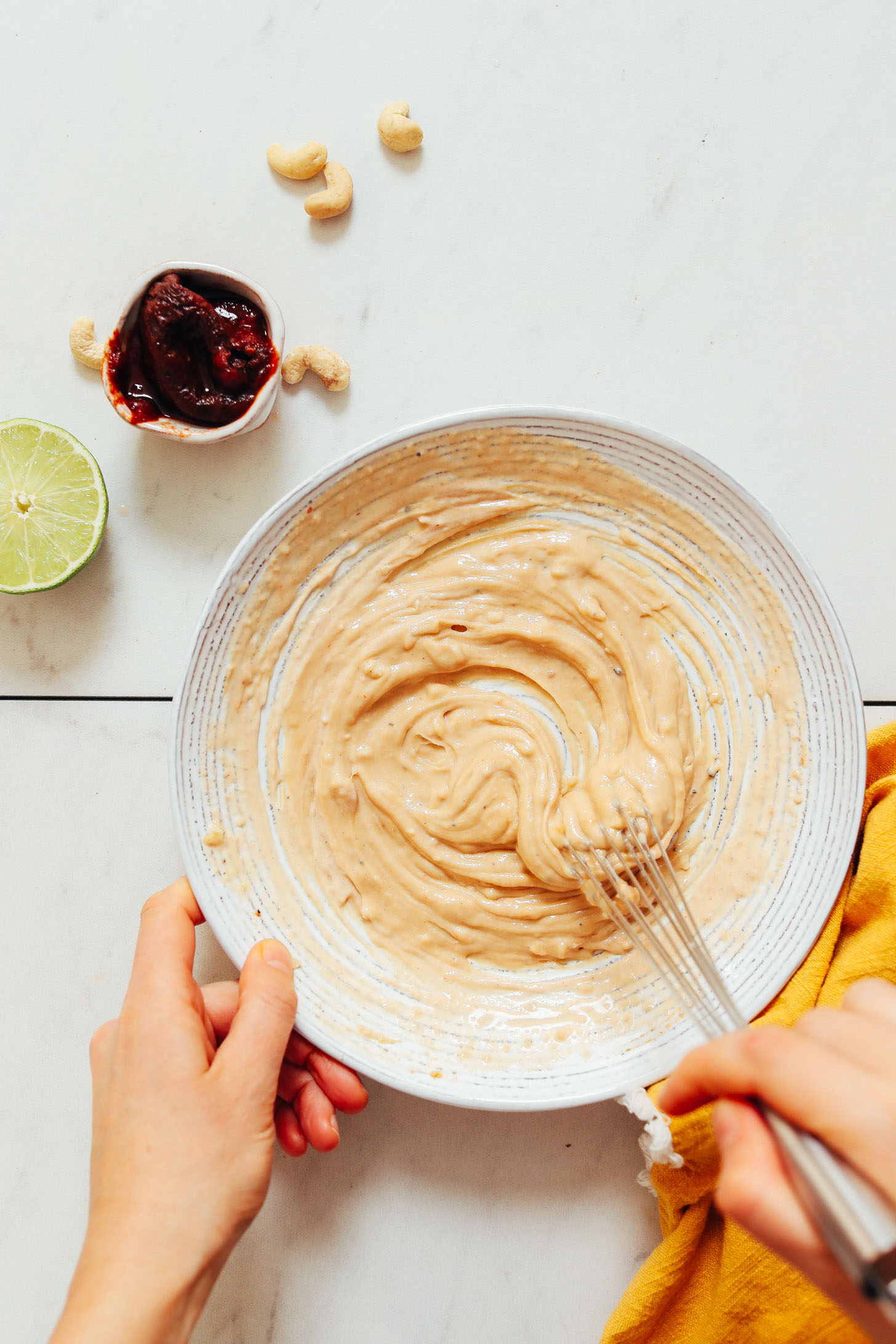 Using a whisk to combine the cashew butter, lime juice, adobo sauce, and other ingredients for our Chipotle Dressing recipe